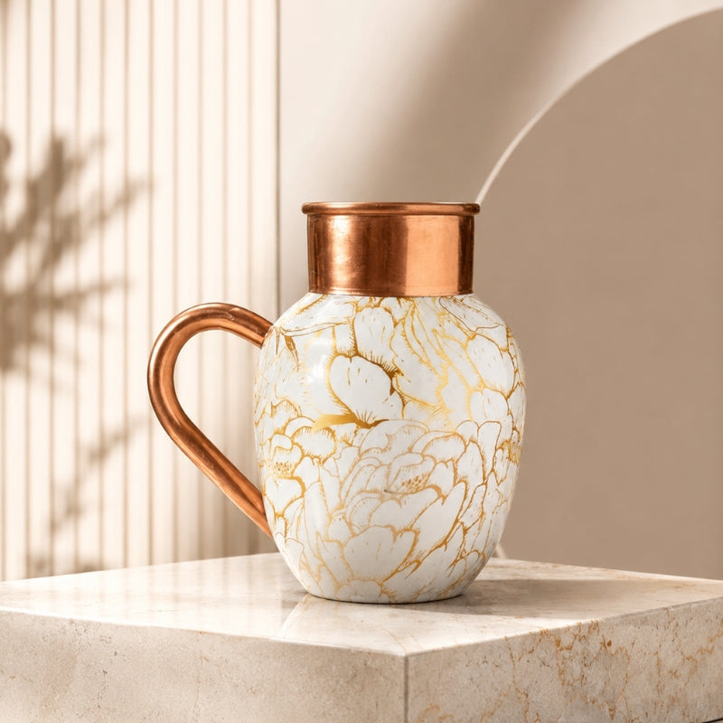 White and gold floral-patterned copper carafe with copper neck and handle on a marble stand