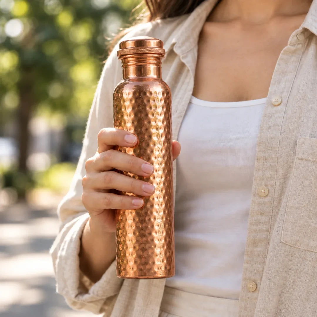 Hand holding the Ashwell pure copper water bottle, lifestyle photo